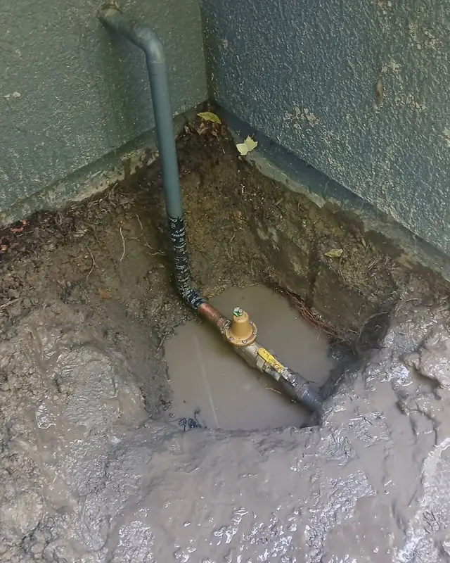 Water-filled excavation around a pipe on a Jeff's Plumbing job