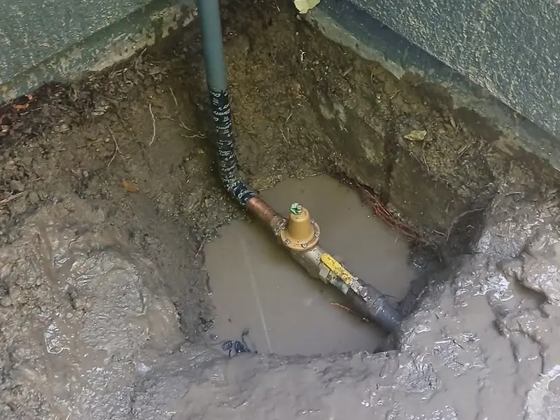 Water-filled excavation around a pipe on a Jeff's Plumbing job